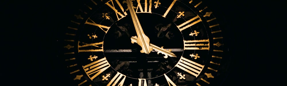 Gold clock face glowing against a black night